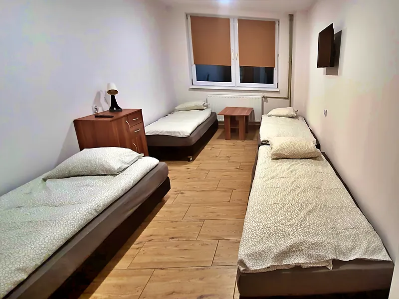 Kwatery pracownicze na Białołęce, pokój 4-osobowy: pokój czteroosobowy z pojedynczymi łóżkami, szafką nocną, stolikiem i telewizorem